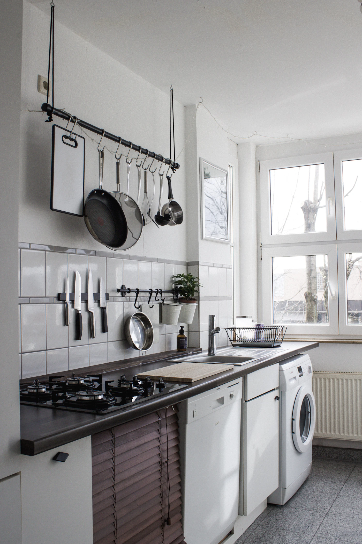 A kitchen with a dishwasher under the counter and pans stored on the wall