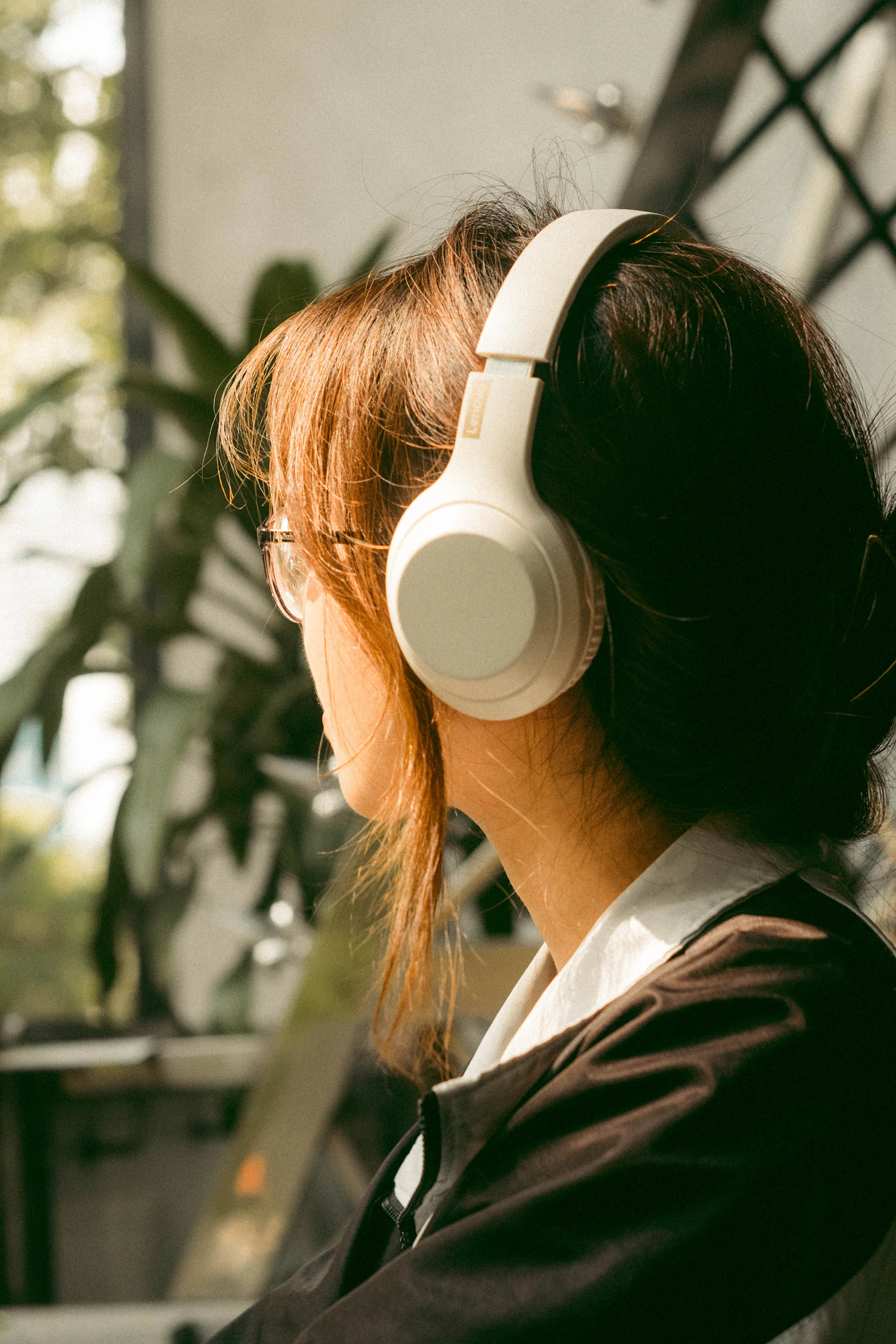 A person listening with over-ear headphones in a sunlit room